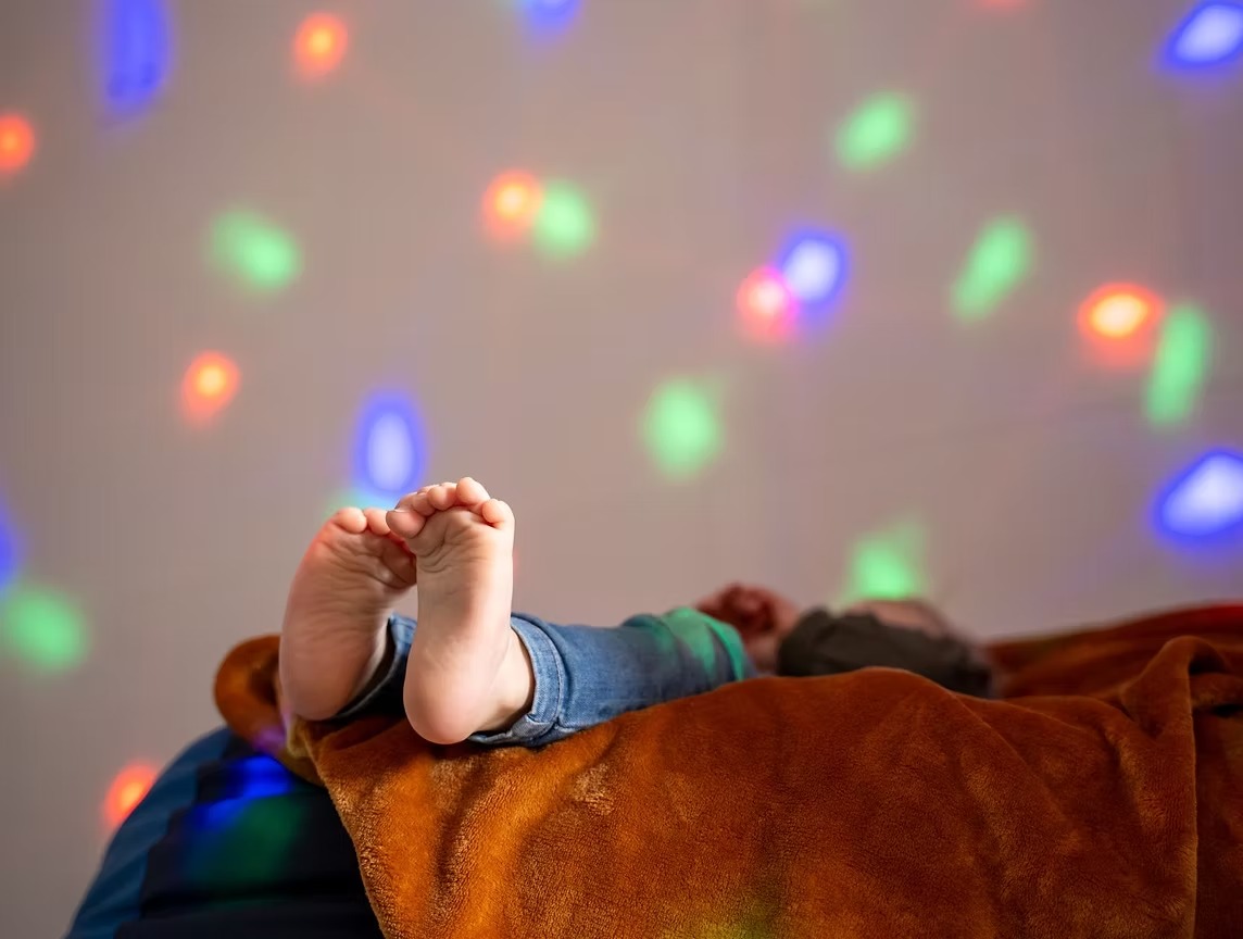Een kindje geniet van kleurrijke lichtjes in het kinderzorghuis
